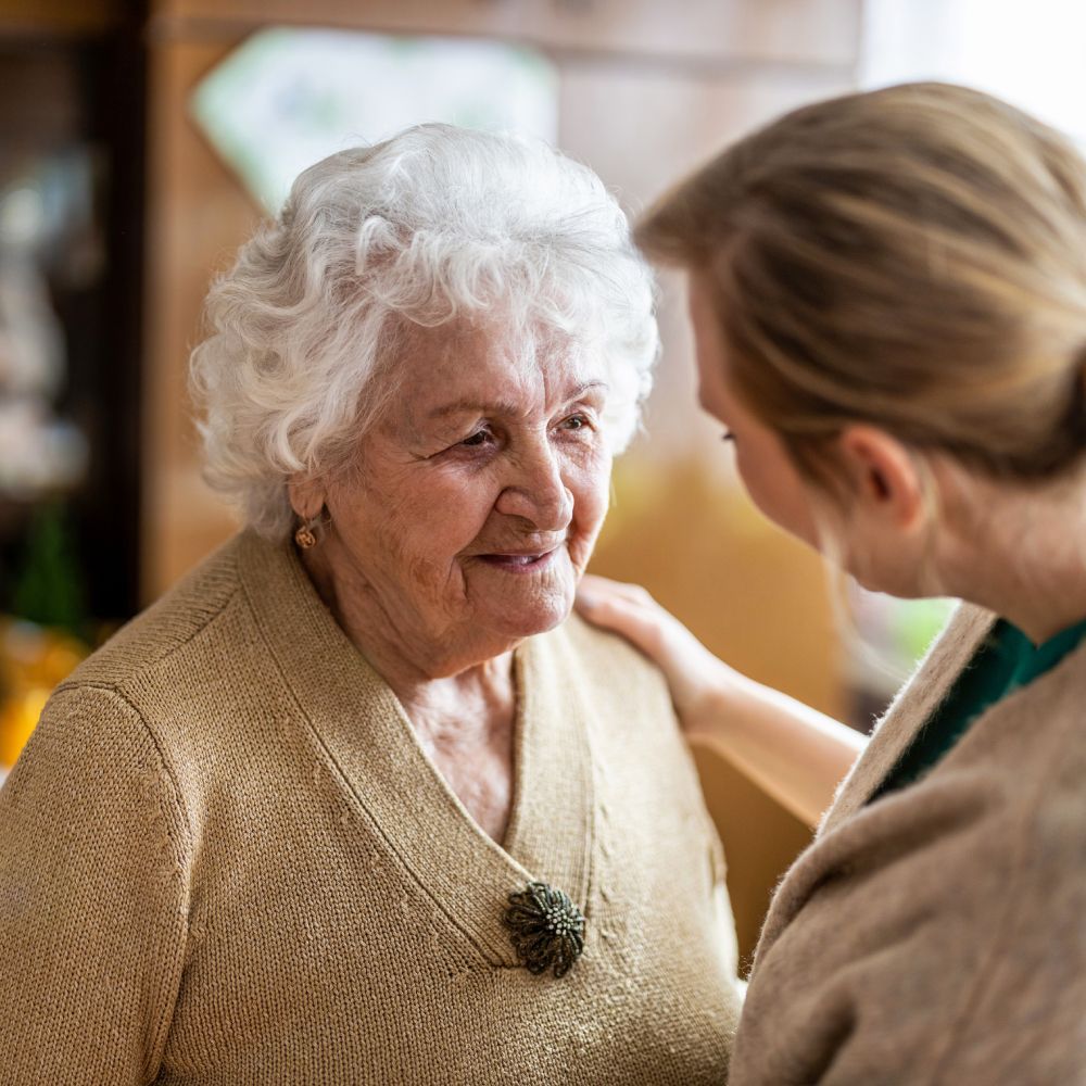 A woman is putting her hand on an older woman 's shoulder.