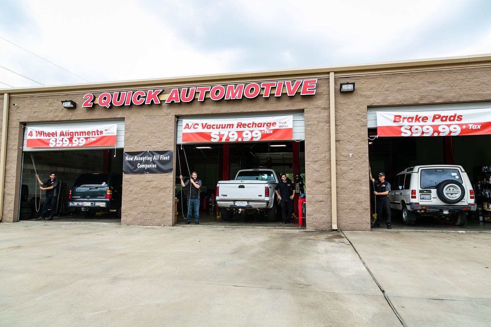 A Quick Automotive shop with three service bays, each displaying service prices and staff standing by vehicles. | 2 QuickAuto, Car & Tire Repair | Copperfield