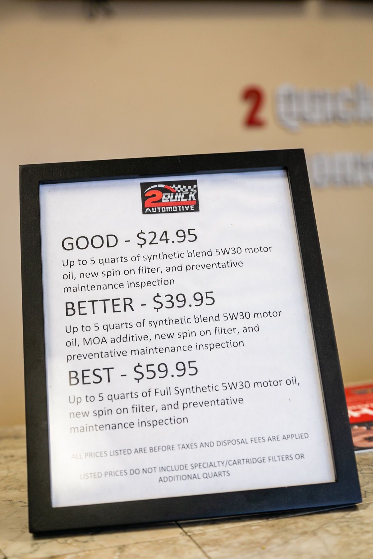 A framed sign lists oil change service tiers: Good ($24.95), Better ($39.95), and Best ($59.95) for an auto shop. | 2 QuickAuto, Car & Tire Repair | Copperfield