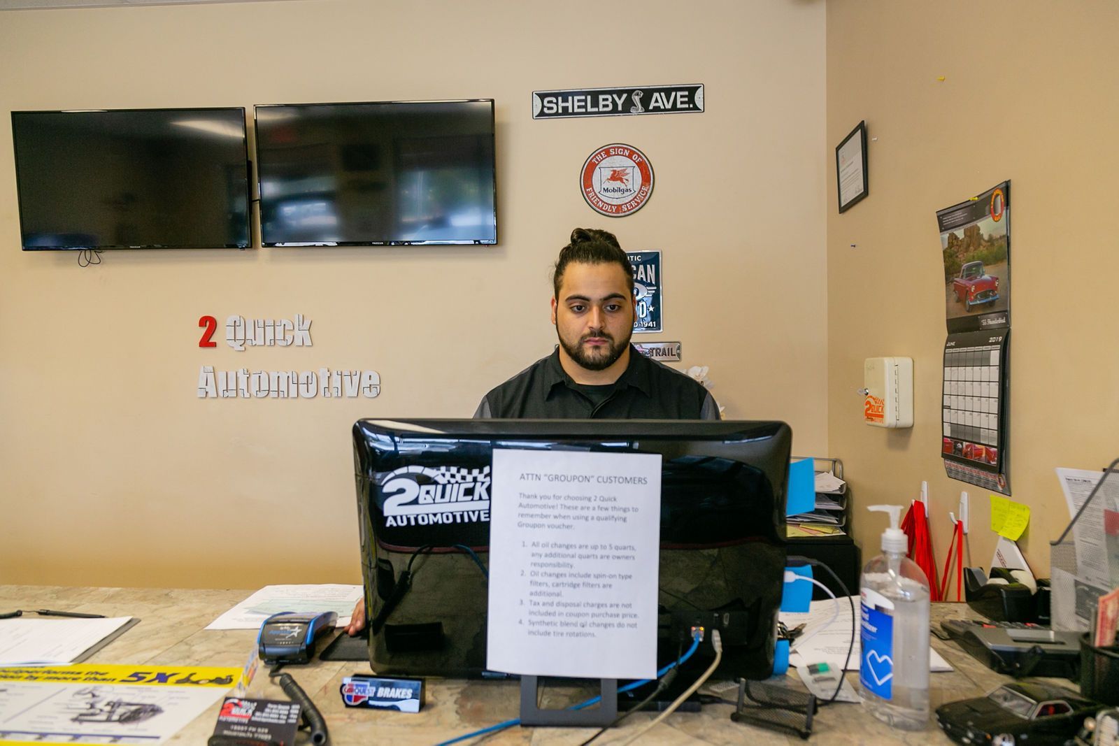 A staff member sits at a desk with a computer monitor at a business labeled 