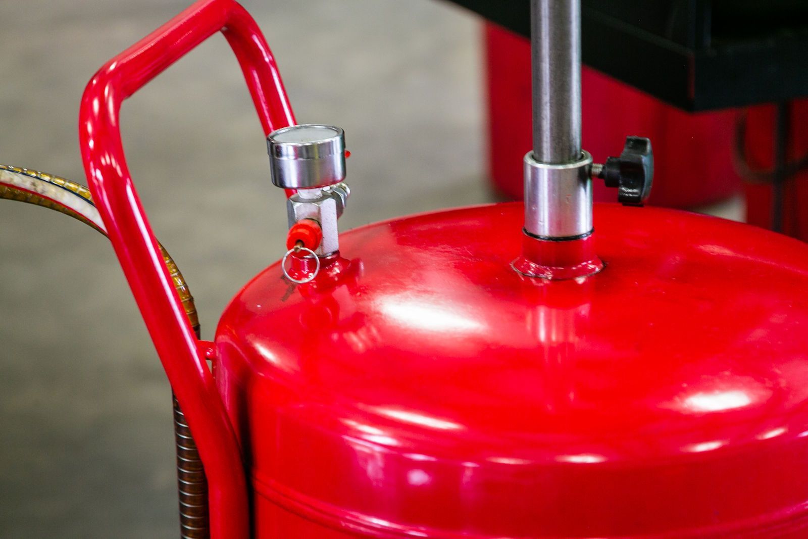 A close-up of a bright red metal tank with a handle, vertical pipe, and a pressure valve attached to its top. | 2 QuickAuto, Car & Tire Repair | Copperfield