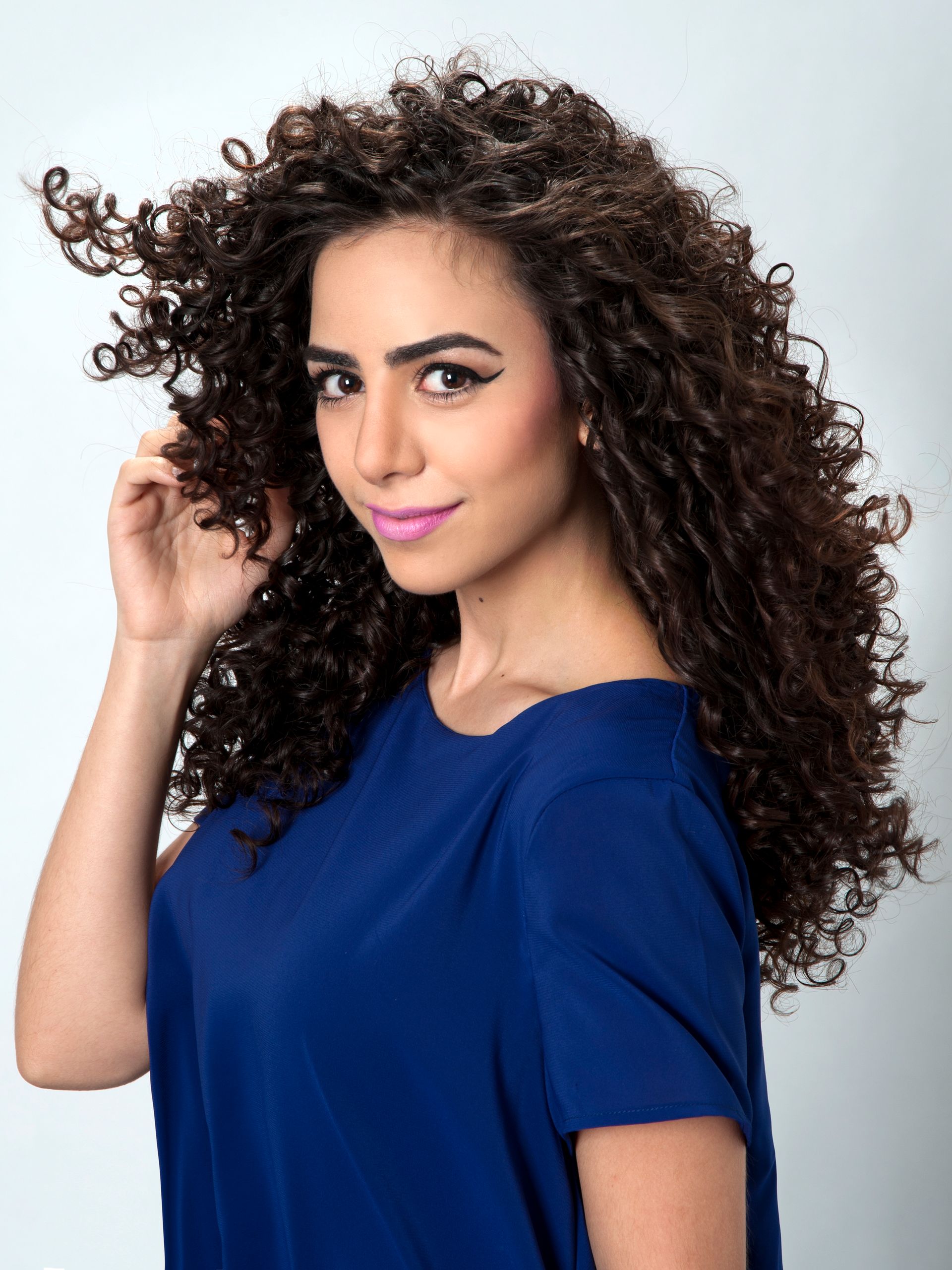 A woman with curly hair is wearing a blue shirt.