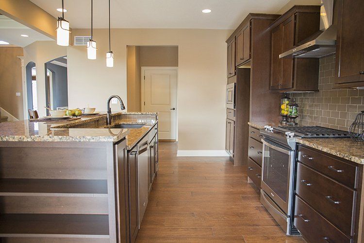 Kitchen With Brown Cabinets & Pendant Lights by Hansman Custom Homes in Mid-Missouri