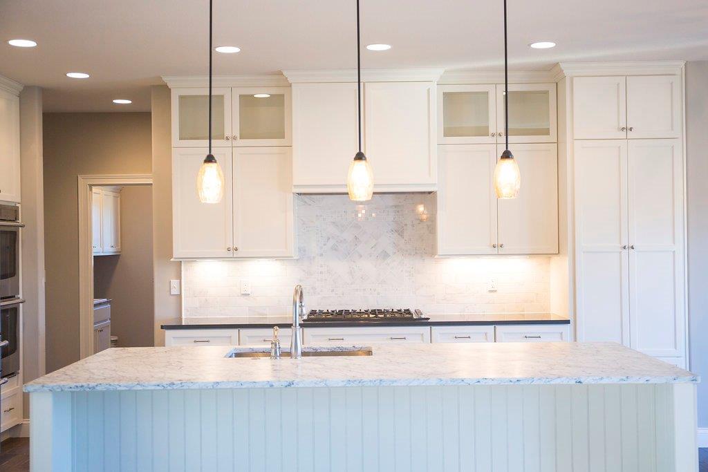 White Kitchen With Pendant Lighting by Hansman Custom Homes in Mid-Missouri