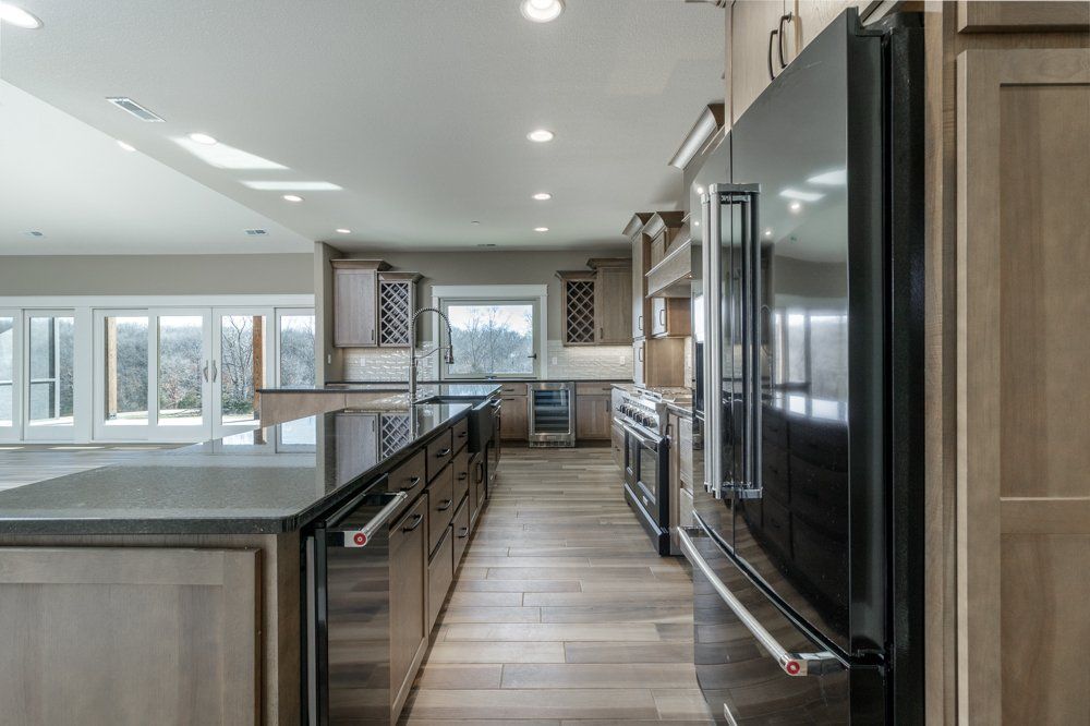 Sleek Black & Brown Kitchen With Windows by Hansman Custom Homes in Mid-Missouri