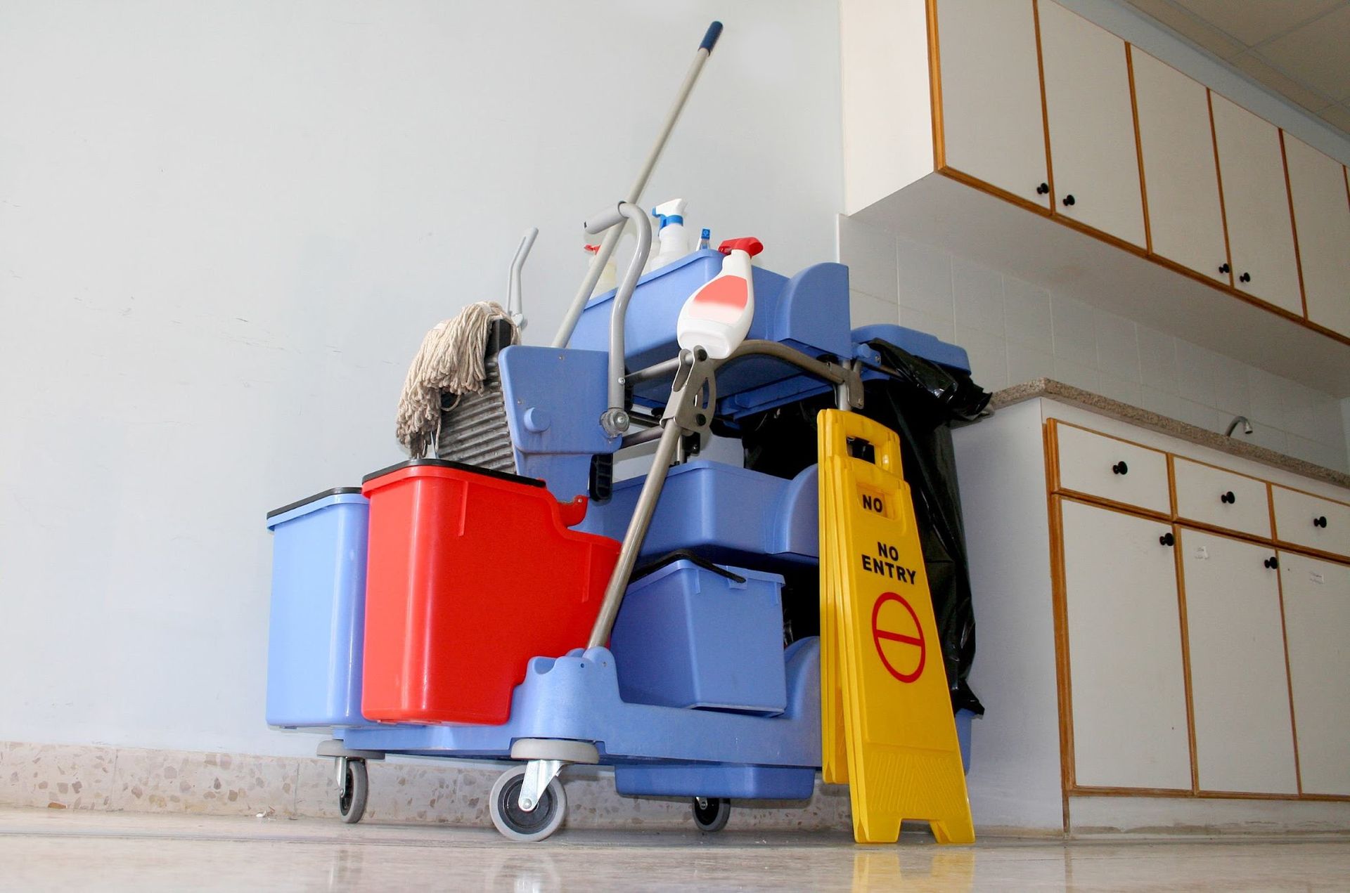 A cleaning cart with a yellow caution sign on the floor