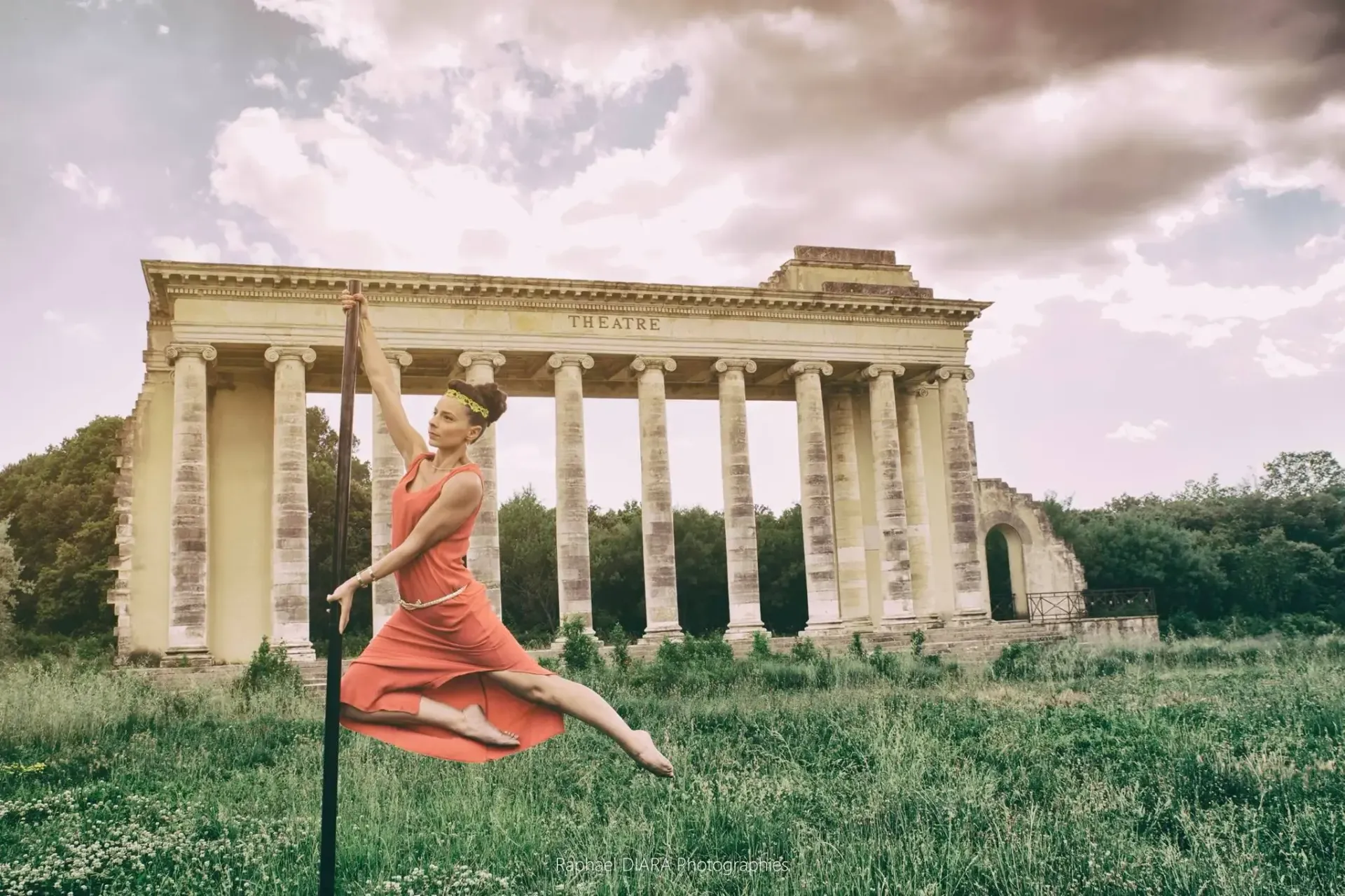Une femme en robe rouge saute en l'air devant un bâtiment ancien.