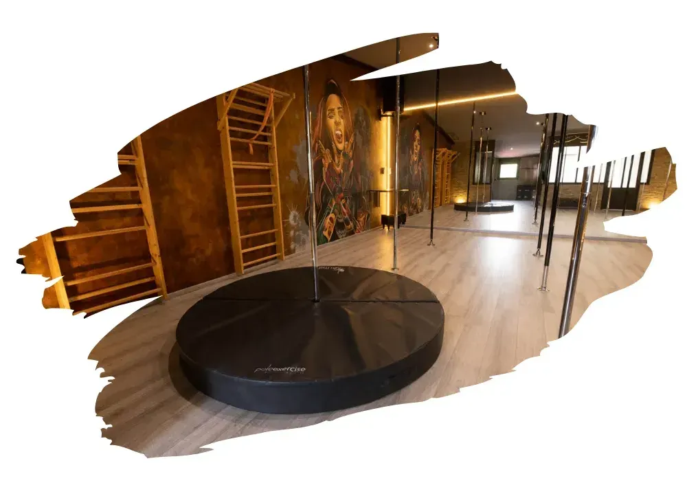 Un studio de pole dance avec une peinture d'une femme sur le mur.