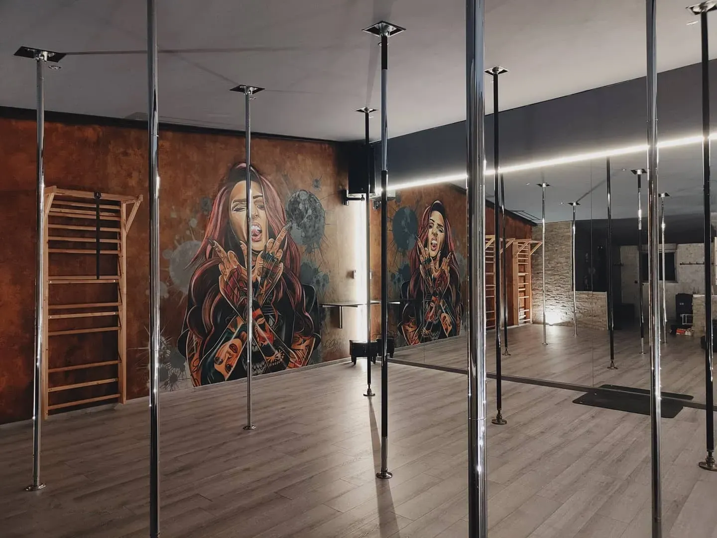 Un studio de pole dance avec une peinture d'une femme sur le mur.