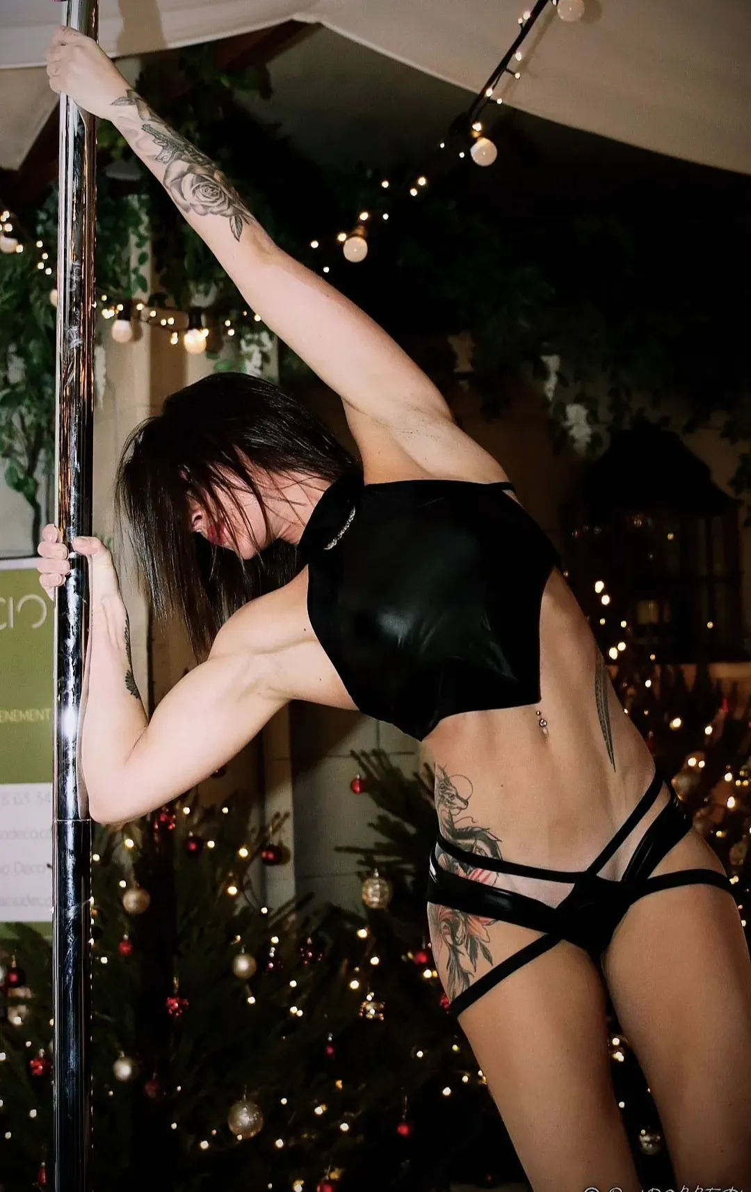 Une femme est debout sur un poteau devant un arbre de Noël.