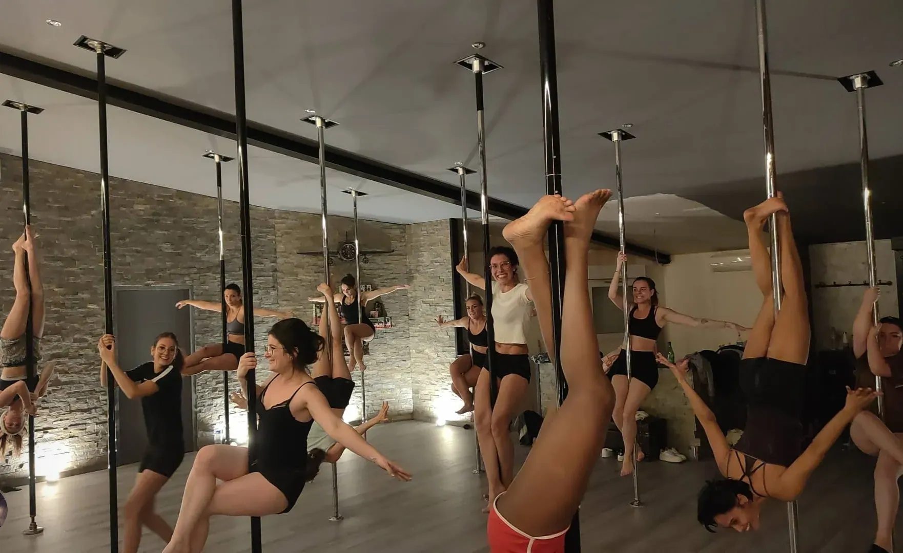 Un groupe de personnes fait de la pole dance dans une salle de sport.