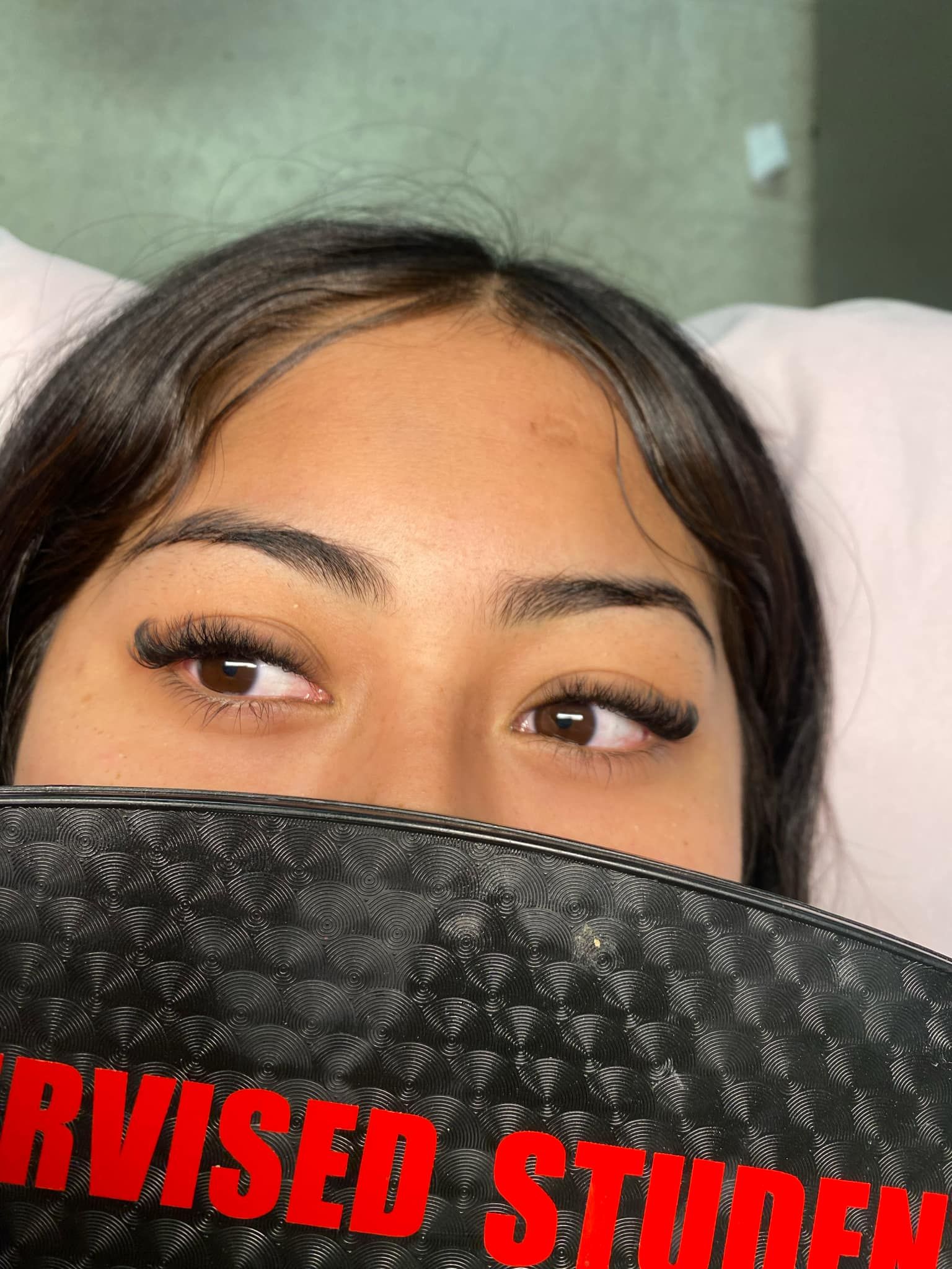 A close up of a woman covering her face with a black purse.