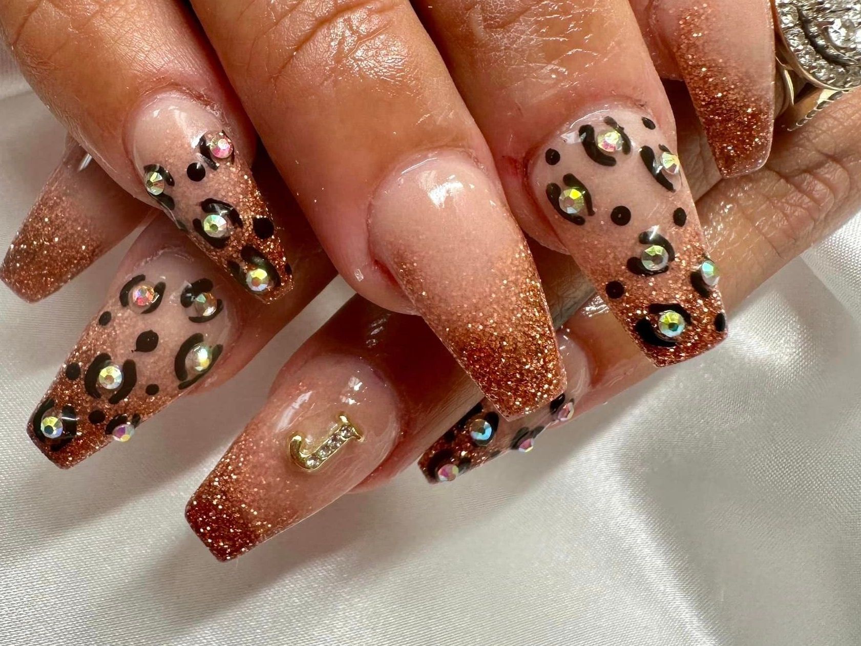 A close up of a woman 's nails with a leopard print and rhinestones.
