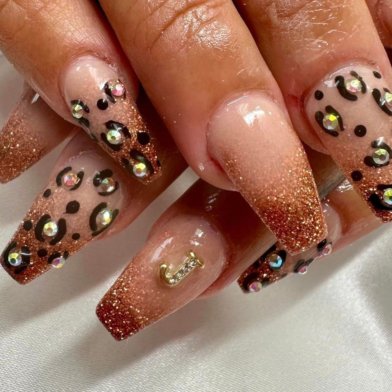 A close up of a woman 's nails with leopard print and rhinestones