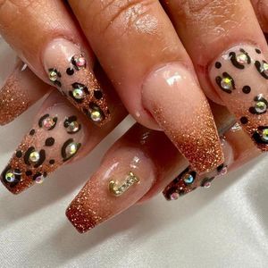 A close up of a woman 's nails with leopard print and rhinestones