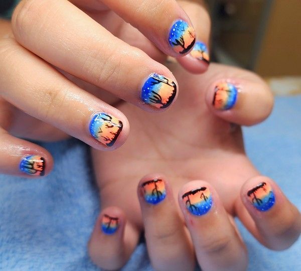 A close up of a person 's nails with palm trees painted on them