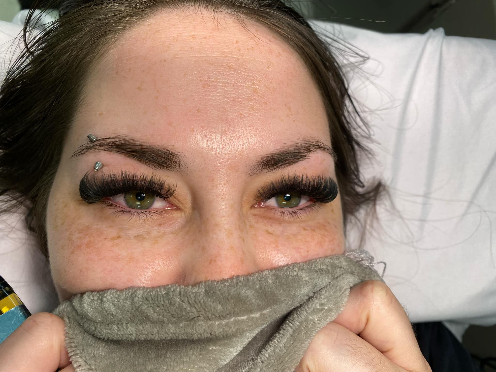 A close up of a woman covering her face with a towel.