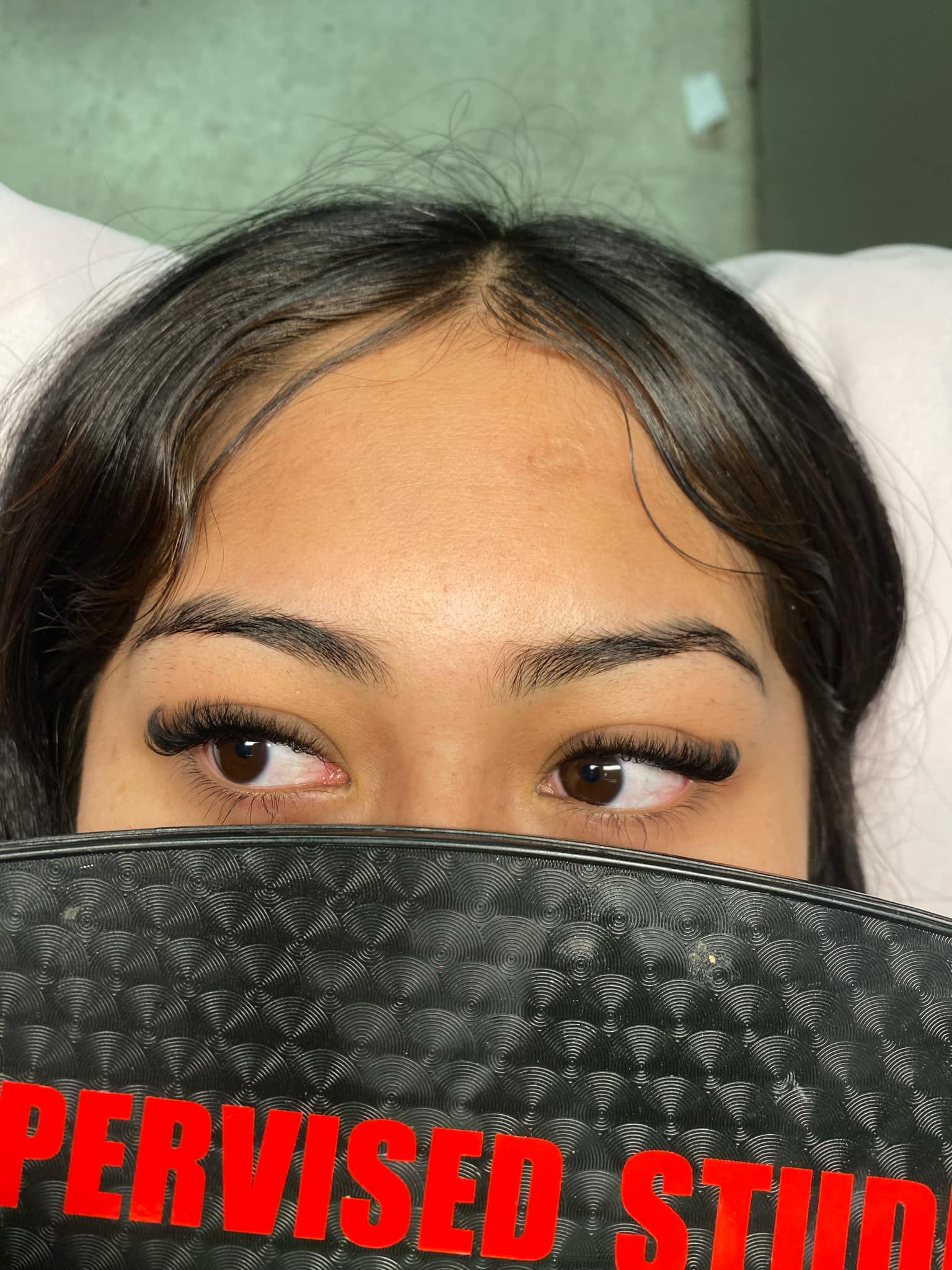 A close up of a woman covering her face with a black purse.
