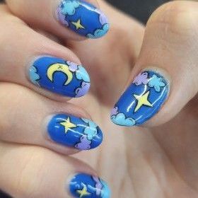 A close up of a person 's nails with a crescent moon and stars on them.