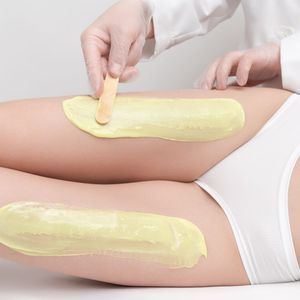 A woman is getting her legs waxed by a doctor