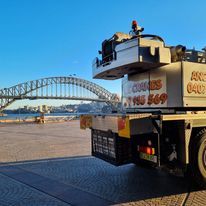 A tow truck is parked in front of a bridge in sydney.