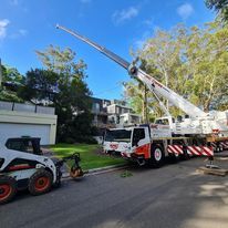 A crane is sitting on top of a truck next to a bobcat.