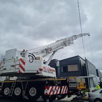 A large crane is parked in front of a building.