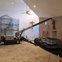 A crane is being used to lift a cross in a church.