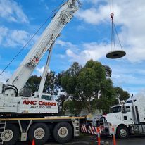 A truck with a crane attached to it is lifting a large object.