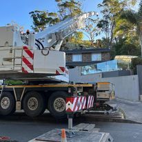 A large crane is parked on the side of the road in front of a house.