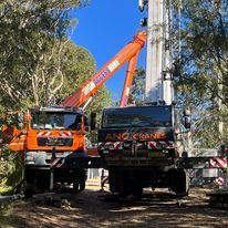 A truck with a crane attached to it is parked in the woods.
