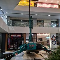 A large green crane is sitting in the middle of a building.