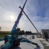 A crane is sitting on top of a concrete surface on a construction site.