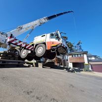 A truck is being towed by a crane down a hill.