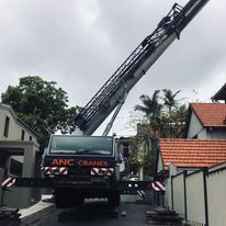 A large crane is sitting on top of a truck in front of a house.