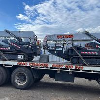 A tow truck with two tractors on the back of it.