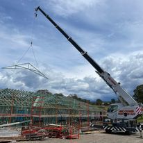 A large crane is lifting a metal structure on a construction site.