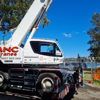 A white crane truck is parked on the side of the road.