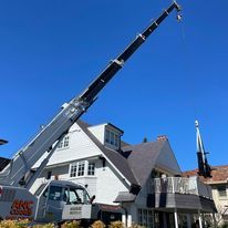 A large crane is sitting in front of a house.