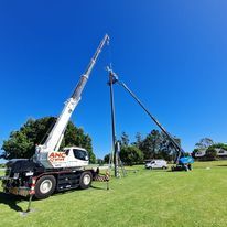 A truck with a crane attached to it is parked in a grassy field.