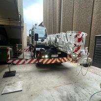 A large crane is parked in front of a building.