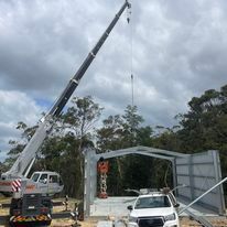 ANC crane lifting a metal structure in a field.