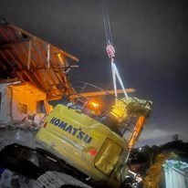 A yellow komatsu excavator is being lifted by ANC crane hire in Sydney