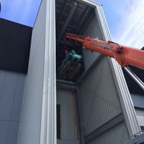 ANC crane is lifting a machine into a building.