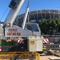 A large crane is parked on a construction site in front of a stadium Sydney
