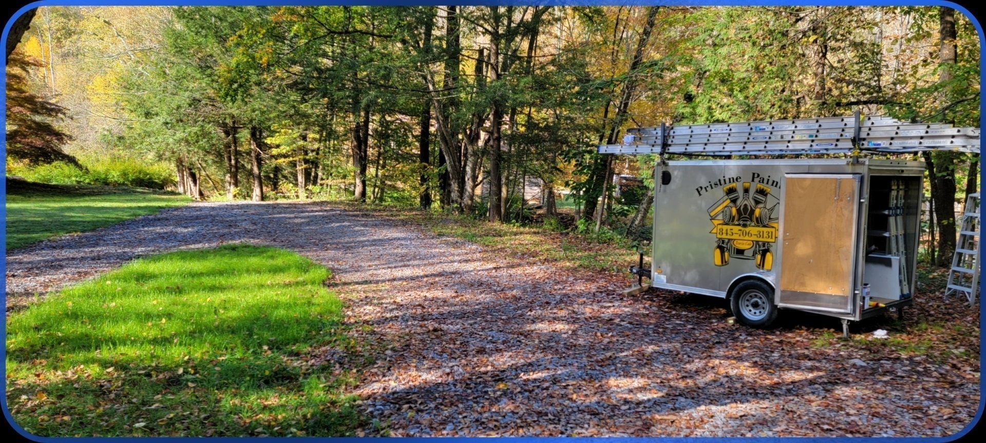 A trailer is parked on the side of a dirt road in the woods.