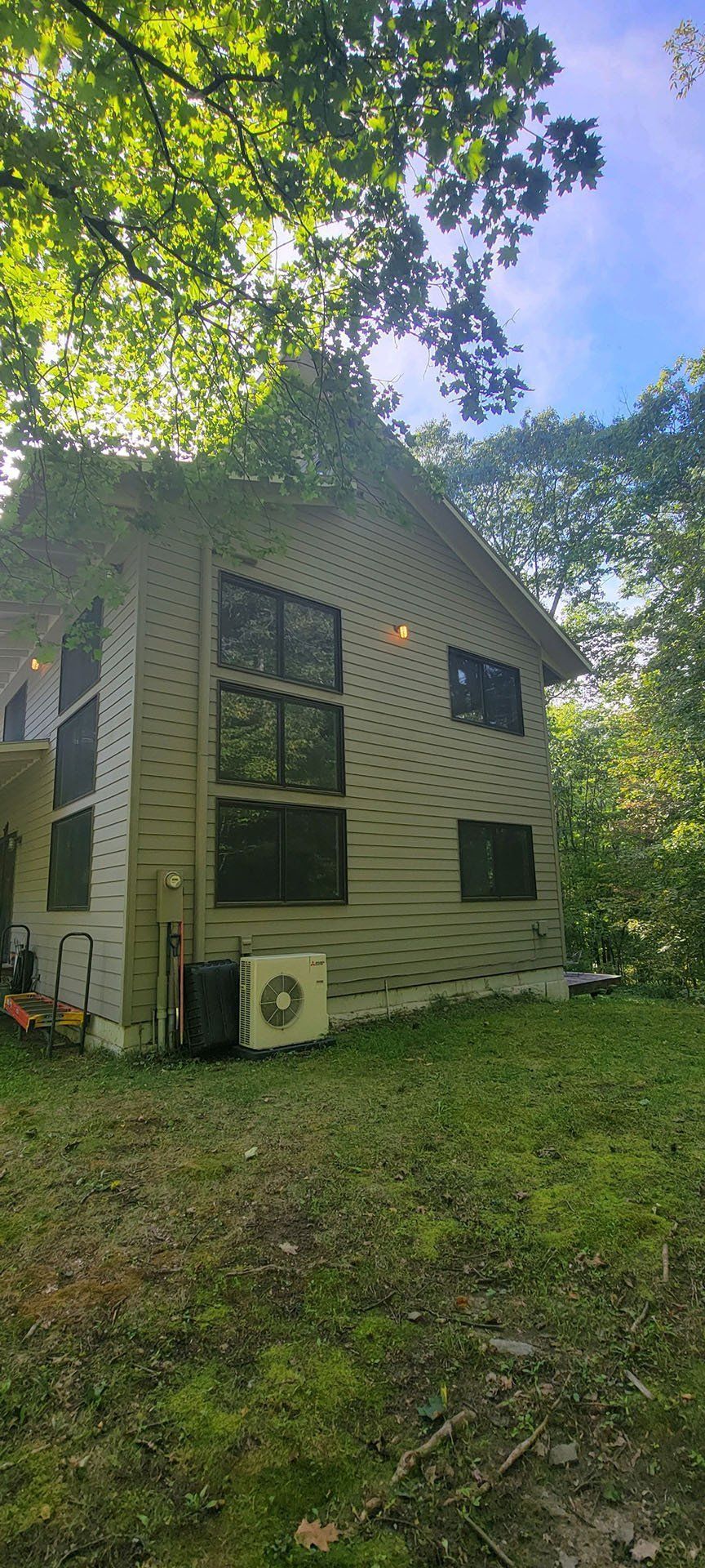 A house with a lot of windows is surrounded by trees and grass.