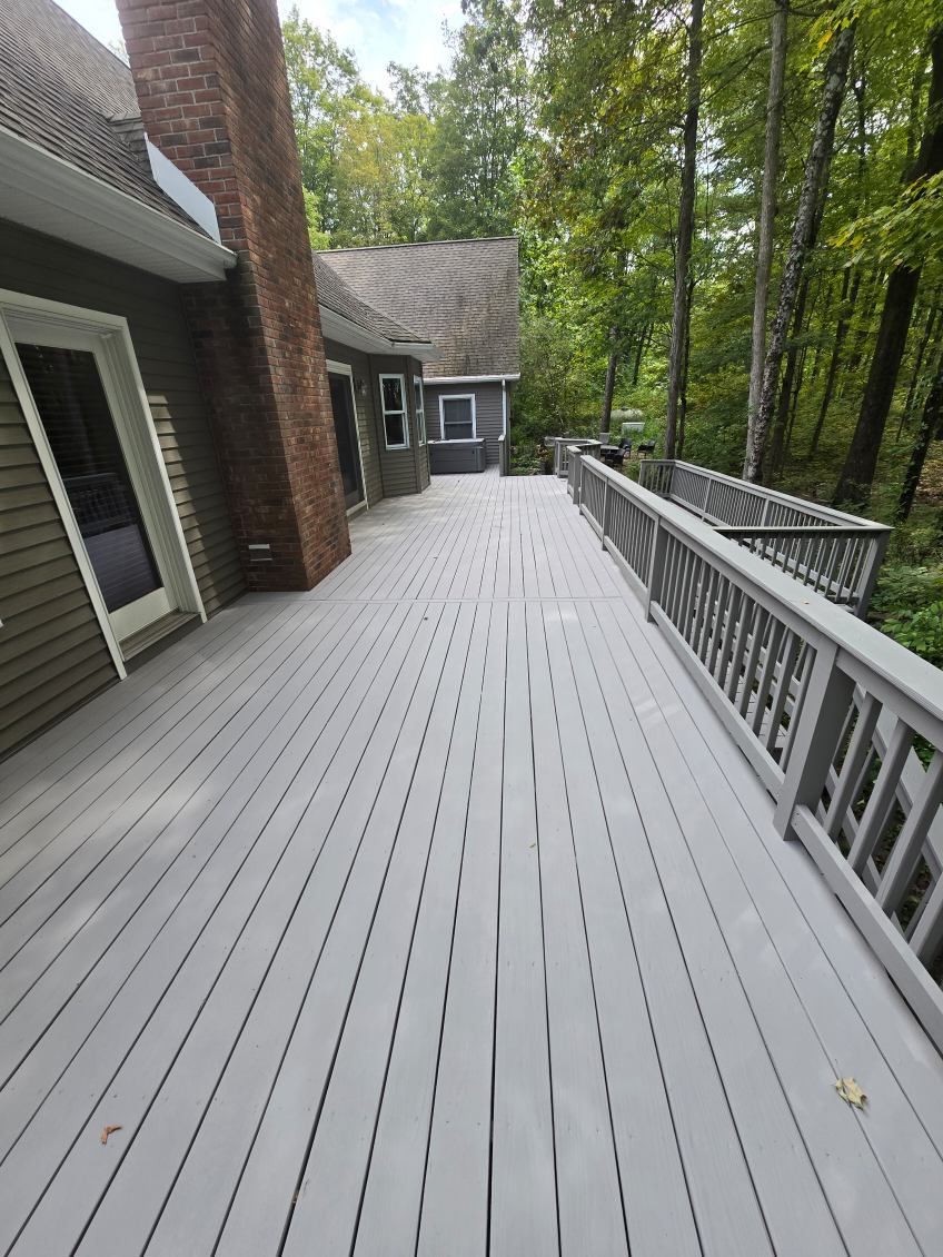 A large wooden deck leading to a house in the woods.