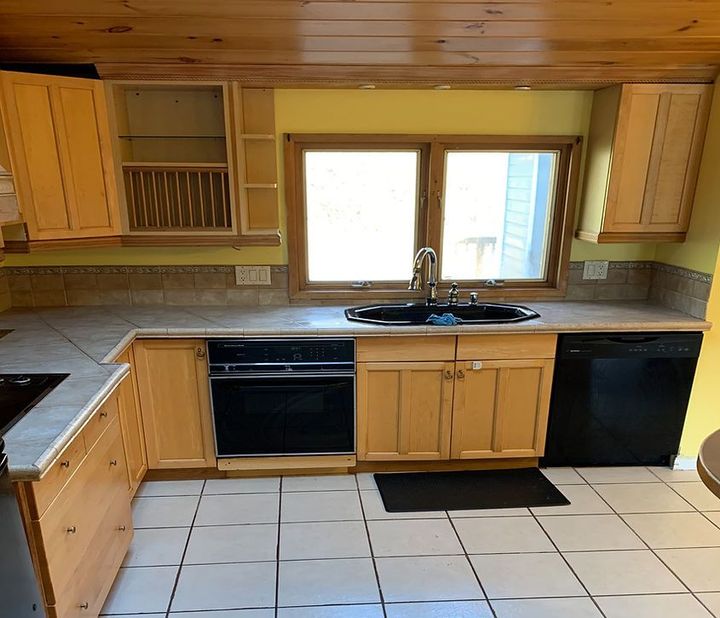 A kitchen with wooden cabinets and a black dishwasher