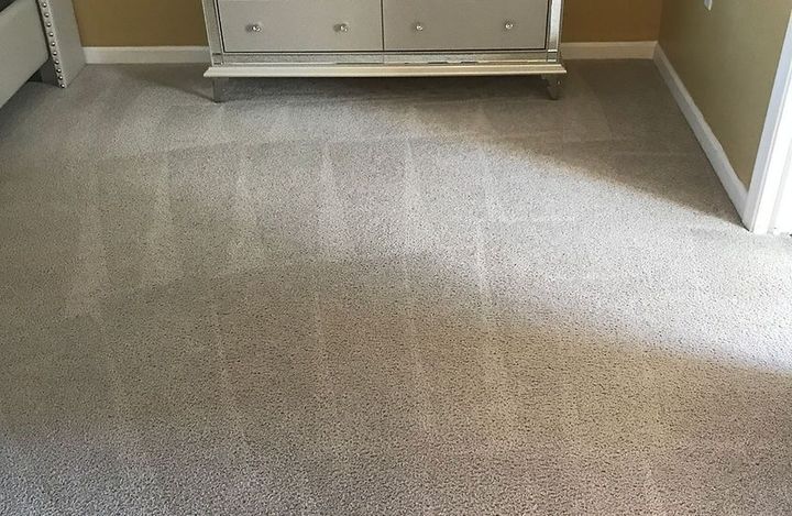 A bedroom with a dresser and a carpeted floor.